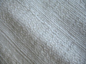 Featured is a macro photo of a vintage textile of the "white" variety.
